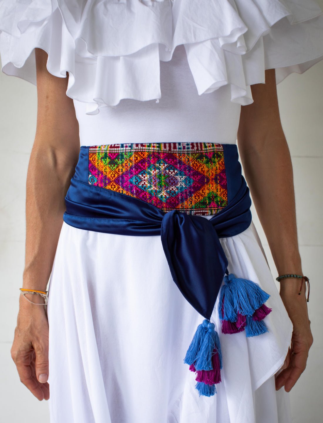 The Eye of Dharma Embroidered Belt includes a colorful and sophisticated silk weave, handwoven by Bhutanese artisans. The weave is attached to a pure silk sash in a royal blue color. The ends of the sash include beautiful tassels.