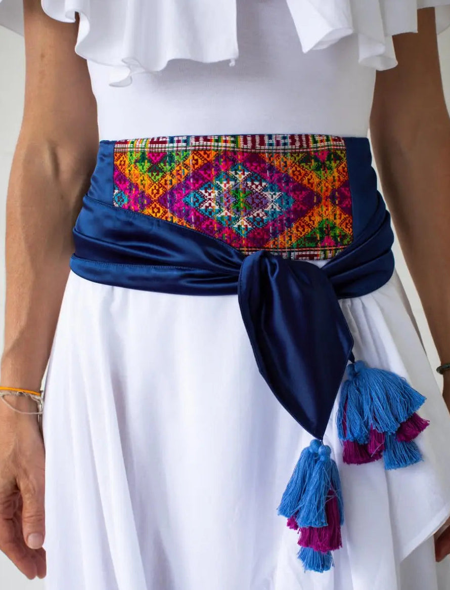 The Eye of Dharma Embroidered Belt includes a colorful and sophisticated silk weave, handwoven by Bhutanese artisans. The weave is attached to a pure silk sash in a royal blue color. The ends of the sash include beautiful tassels.