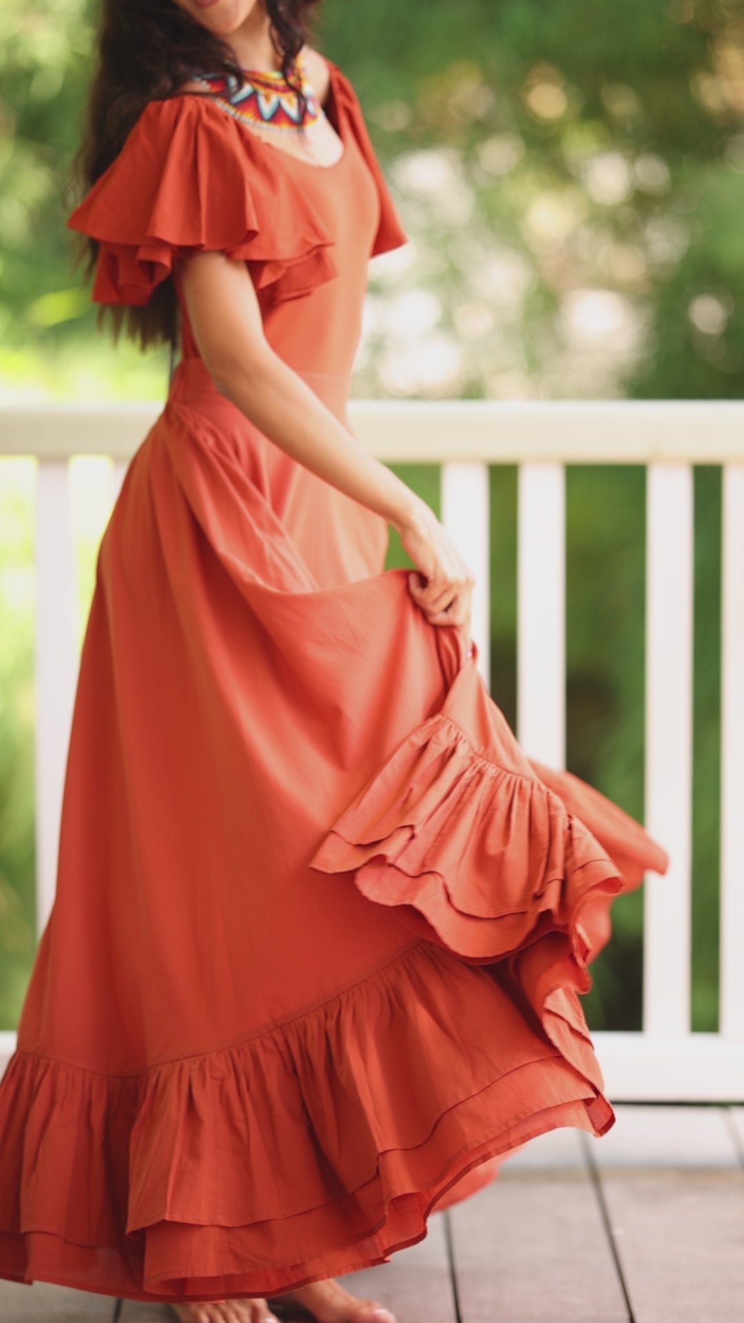 The video shows a woman dancing radiantly in the terracotta Ina Bodysuit and Sacred Hoop of Life Skirt. She looks joyful as she twirls and dances in beauty.